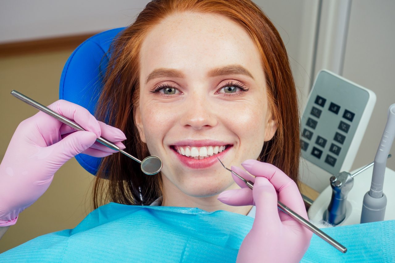 Portrait of an attractive smiling redhaired ginger customer girl in a dental chair.jpg